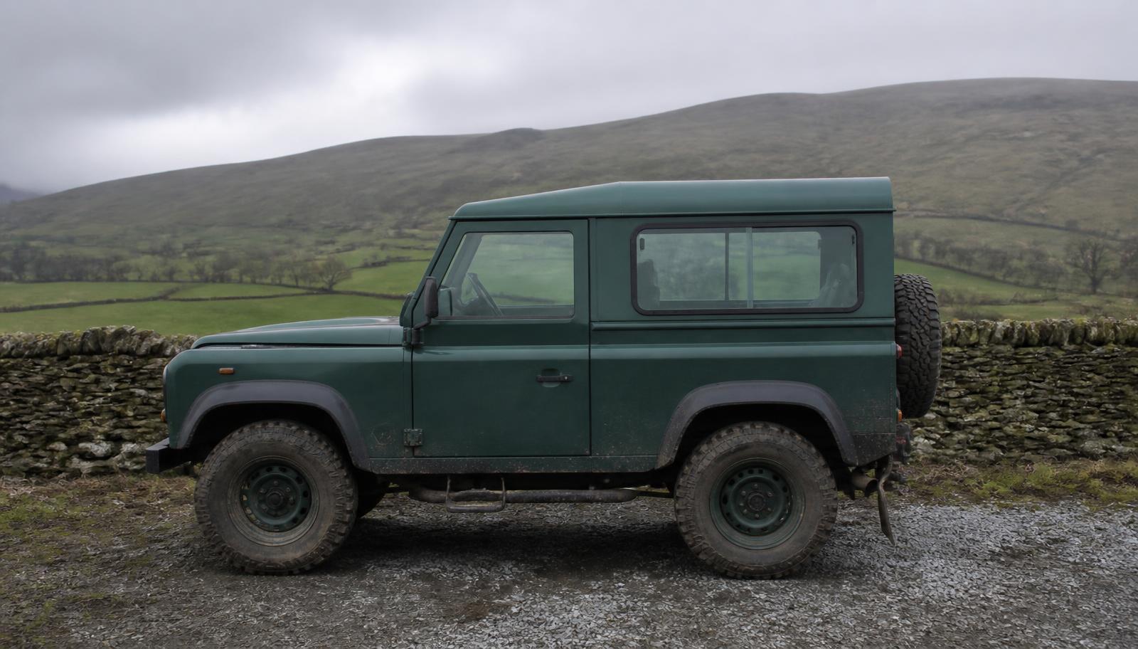 Green Land Rover Defender 90 parked on a gravel yard in the Irish countryside